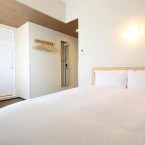 A hotel room with a bed, a door, a coat rack, and a wall-mounted light. - AB Hotel Iga Ueno (Iga)