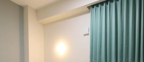 A hotel room with a bed, a small round table, a sofa, and a wall-mounted light.