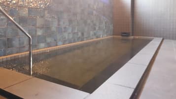 Piscina retangular coberta, com parede revestida de azulejos e corrimão de metal em um dos lados.