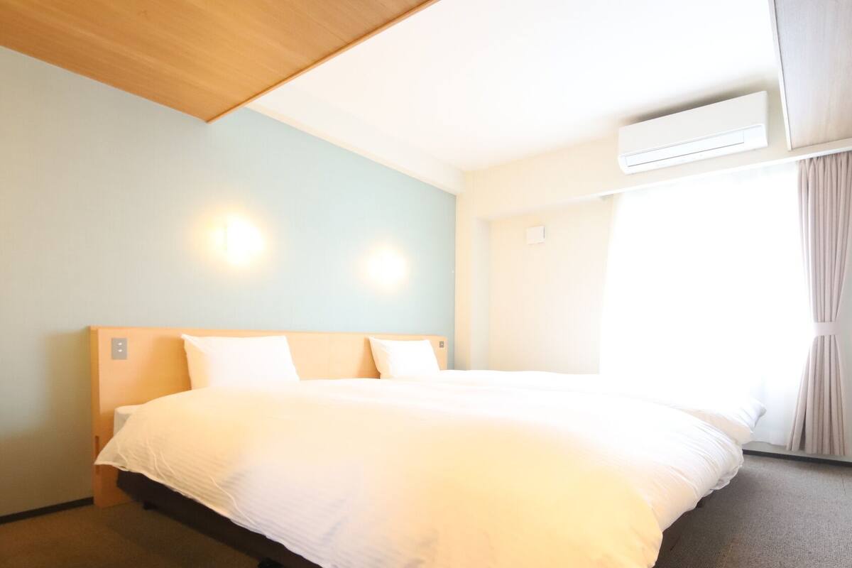 Ein Hotelzimmer mit Bett, Stuhl, Deckenleuchte und Klimaanlage.