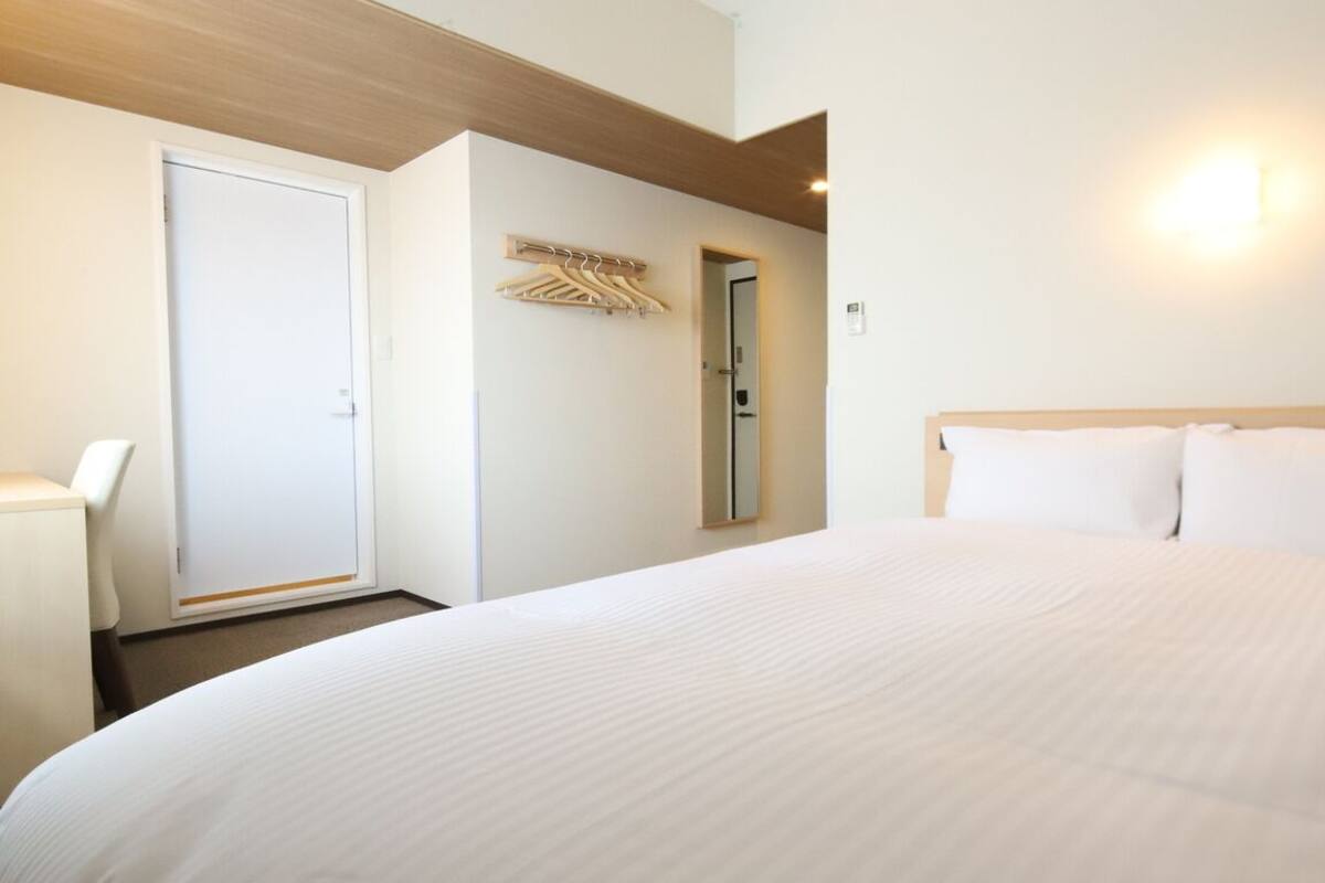 Ein Hotelzimmer mit einem großen Bett, einem Kleiderschrank, einem Spiegel und einer Wandleuchte.