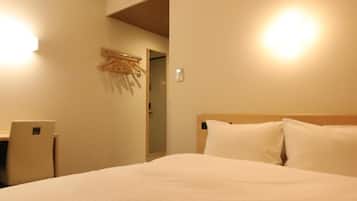Una habitació d'hotel amb un llit, un escriptori i un aparell d'aire condicionat.