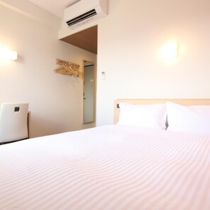 A hotel room with a bed, a wall-mounted air conditioner, a coat rack, and a door leading to another room. - AB Hotel Iga Ueno (Iga)