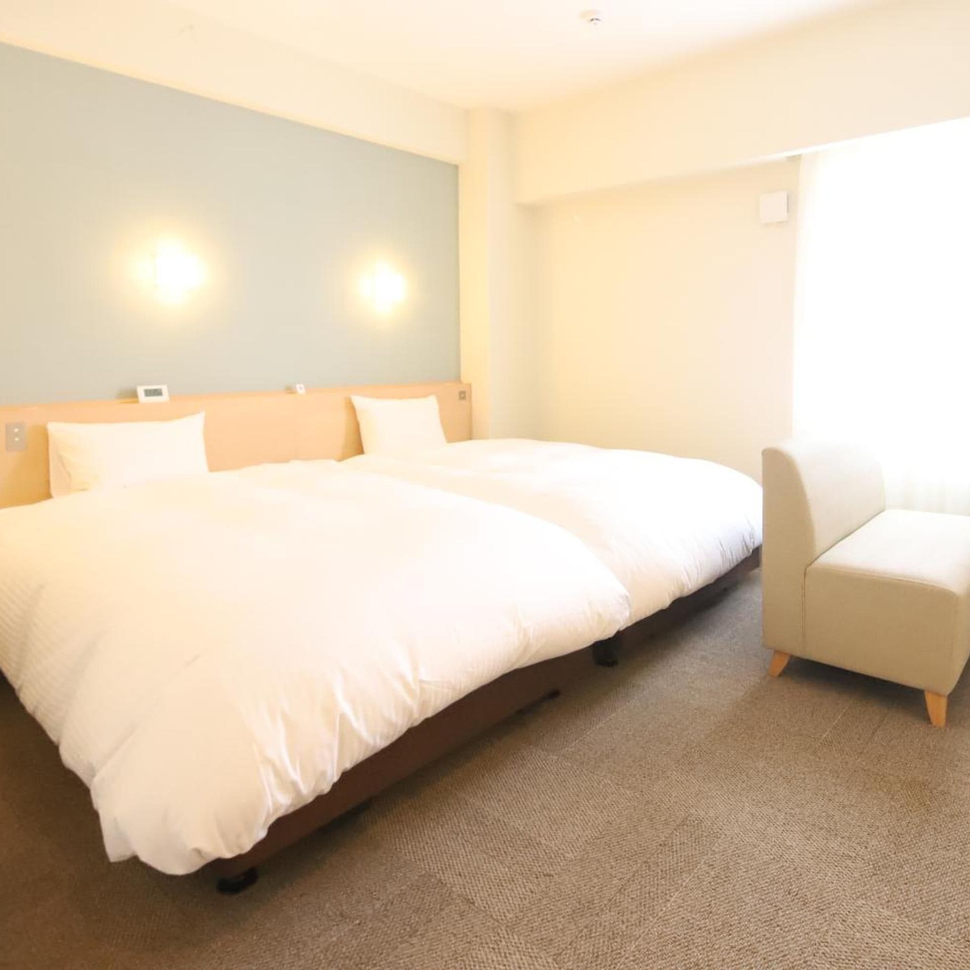 A hotel room with a large bed, a chair, and a light-colored carpet.