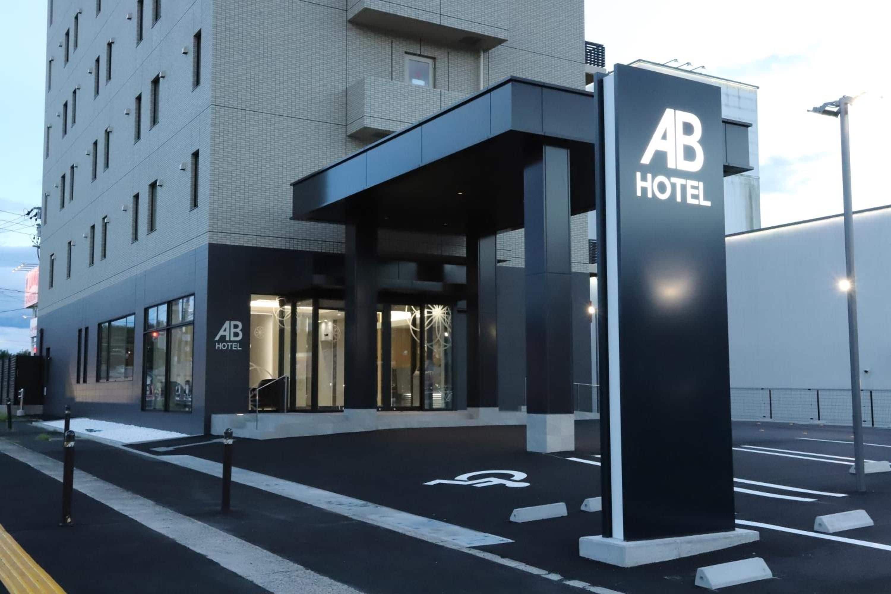 A hotel entrance with a modern design, featuring a prominent signboard and a covered entrance area.