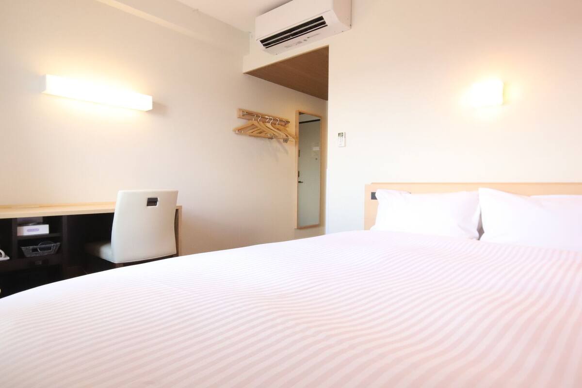 Ein Hotelzimmer mit Bett, Schreibtisch, Stuhl und Klimaanlage.