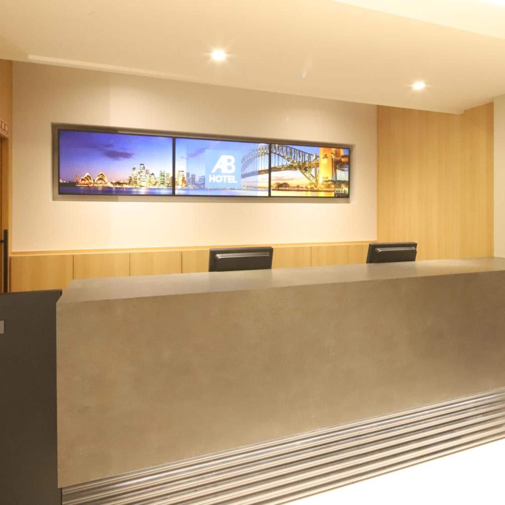 Un salón de conferencias con una larga mesa, dos sillas y una pantalla mural con un paisaje urbano y el logotipo del hotel.