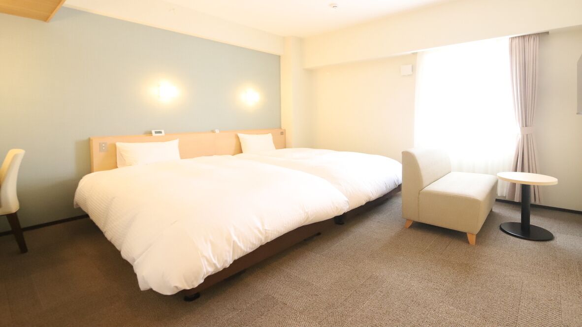 Habitación de hotel con una cama grande, una silla, una mesita y una ventana con cortinas.