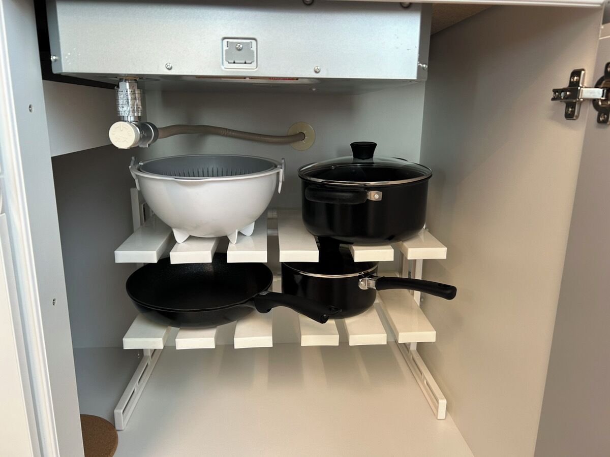 A kitchen with a white countertop, a black frying pan, a white bowl, and a black pot.
