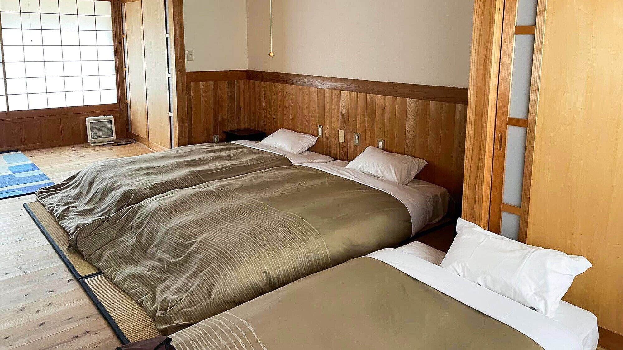 Una habitación con una cama, un calentador y piso de madera.