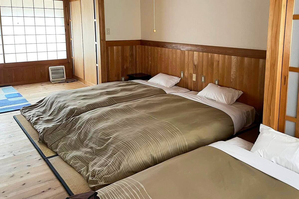 A room with a bed, a heater, and a wooden floor.