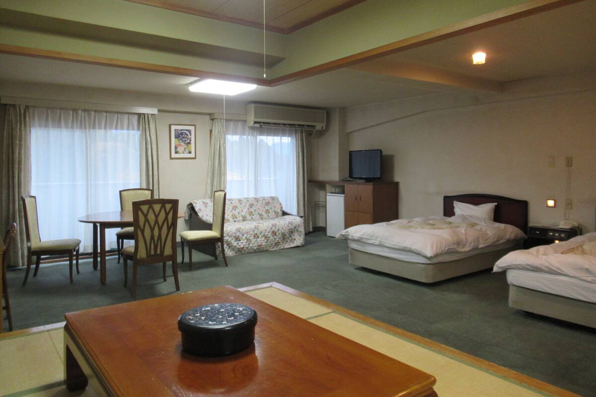 Hotelkamer met een bed, bureau, stoel, televisie en een airconditioning.