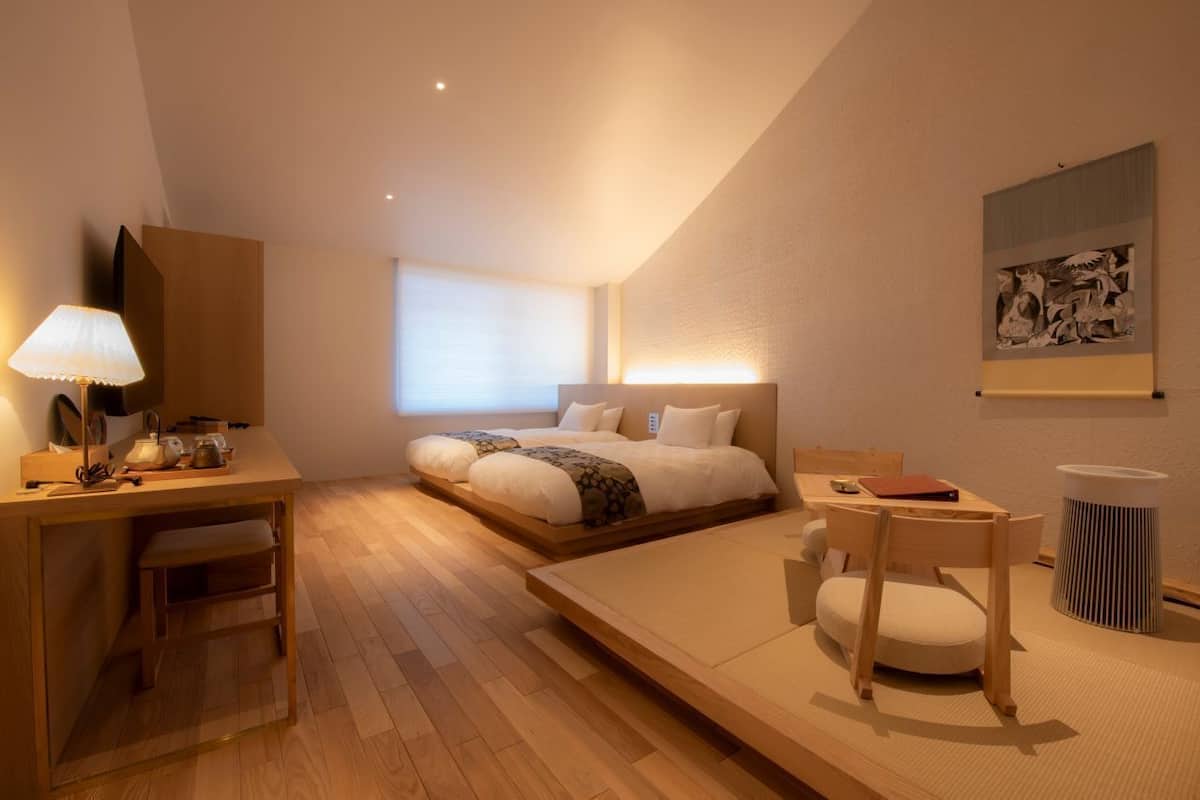 A modern hotel room with a bed, desk, chair, and a small table.