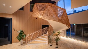 A spiral staircase with geometric patterns, a potted plant, and a view of the sky through a glass door.