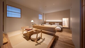 A modern hotel room with a bed, bedside table, lamp, and a view of the outside.