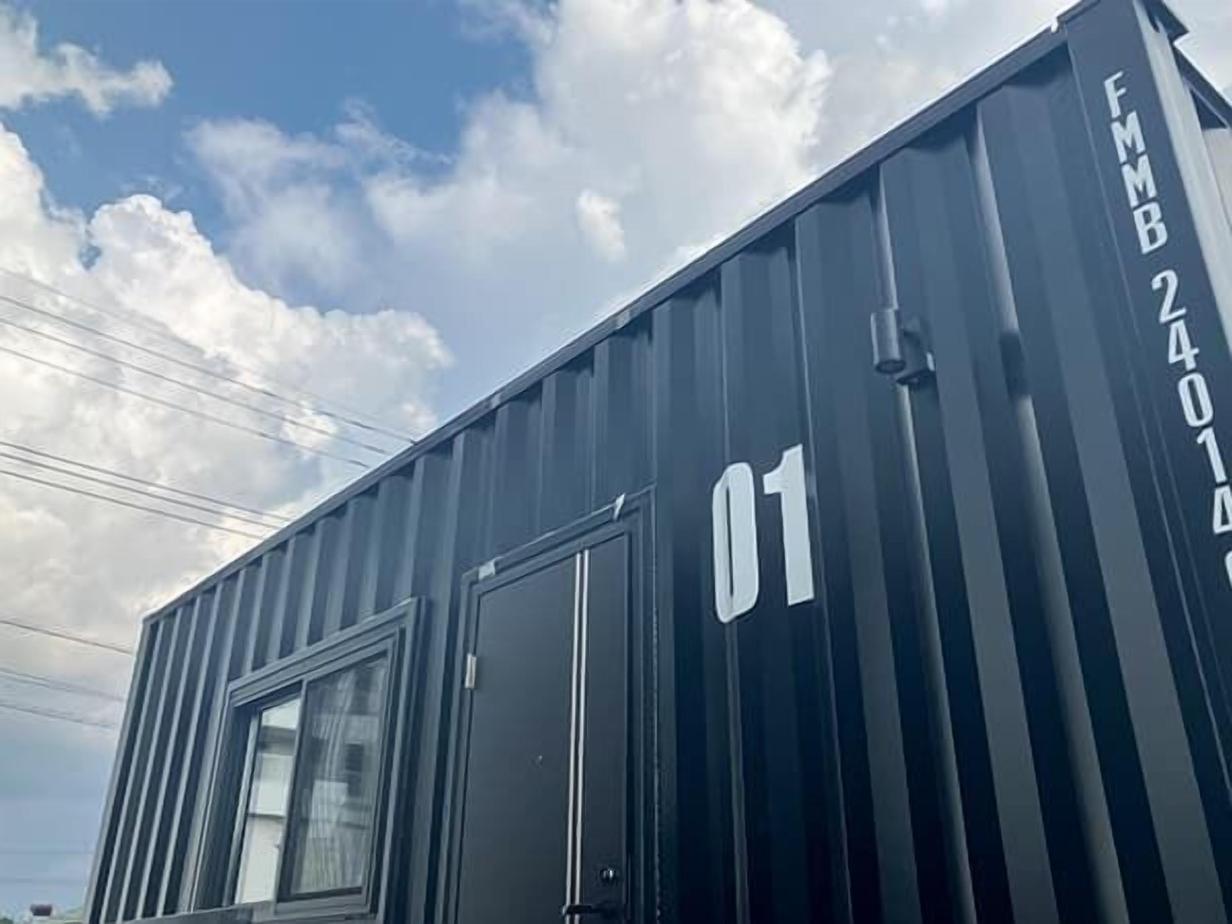 A black shipping container with the number '01' and 'FMB 24014' on it.
