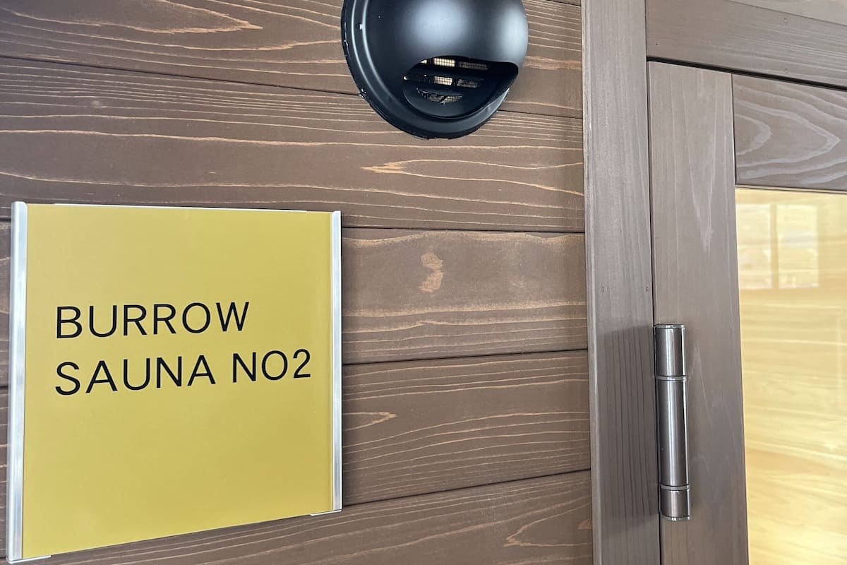 A sign for 'BURROW SAUNA NO2' on a wooden wall.