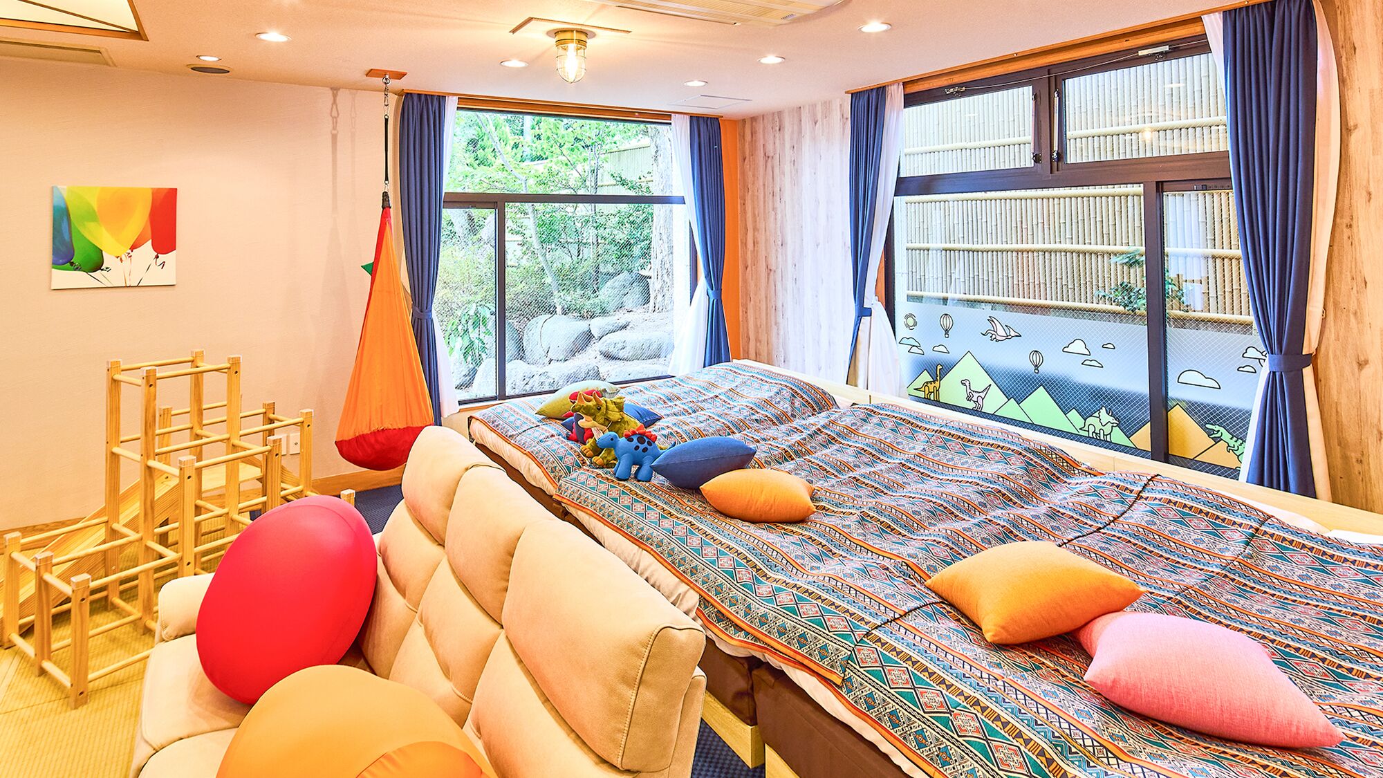 Ein Schlafzimmer mit Bett, Kissen, einem Hängekorbstuhl und einem Fenster mit Blick auf Bäume.