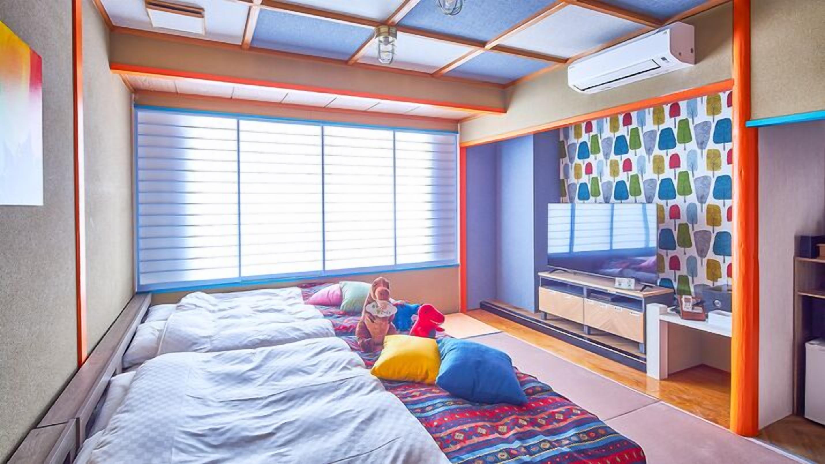Ein Schlafzimmer mit zwei Betten, einem Schreibtisch und einem Fenster mit Jalousien.