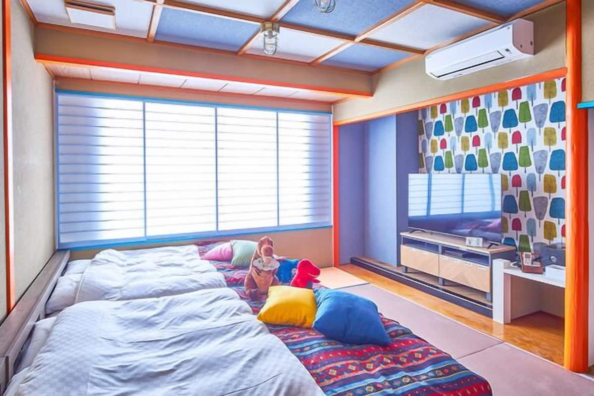 Ein Schlafzimmer mit zwei Betten, einem Schreibtisch und einem Fenster mit Jalousien.