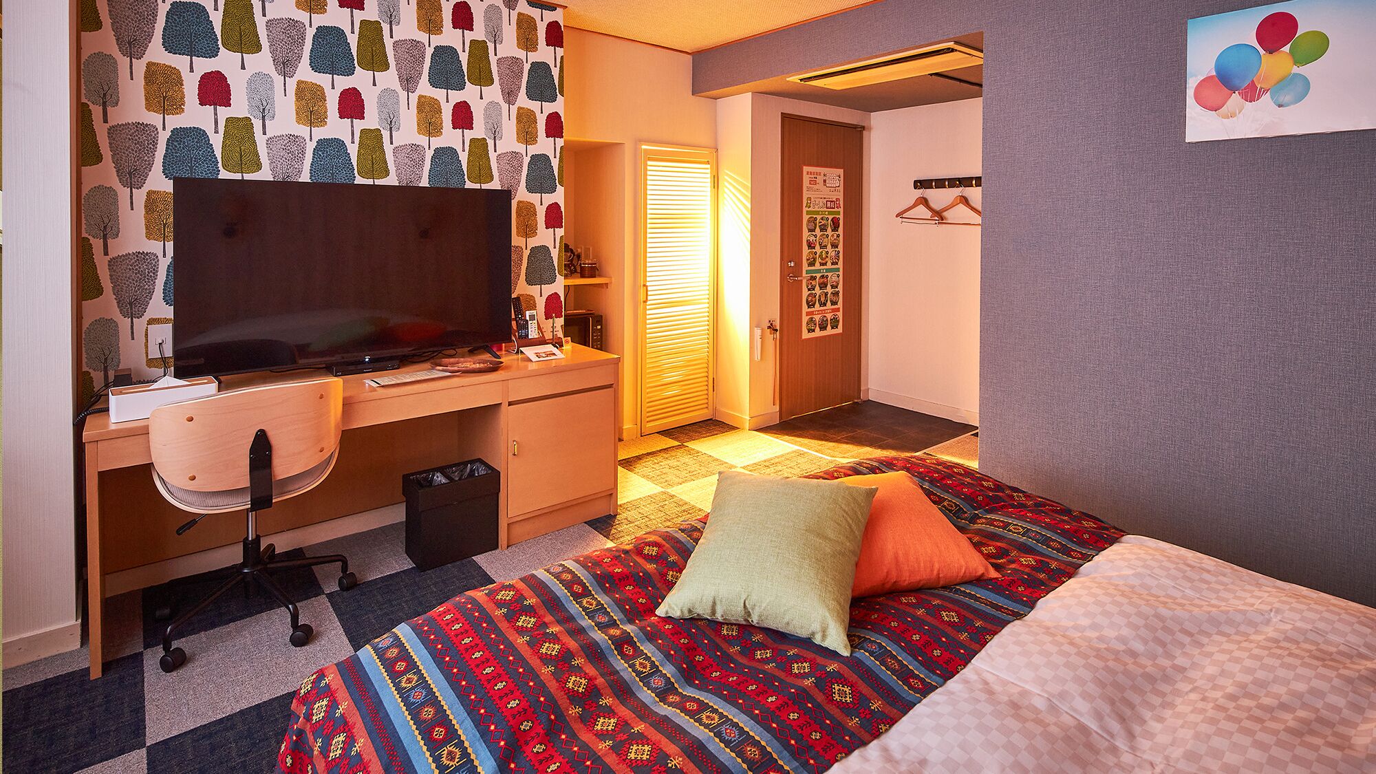 Ein Hotelzimmer mit Bett, Schreibtisch, Stuhl, Fernseher und einer Wand mit Muster.