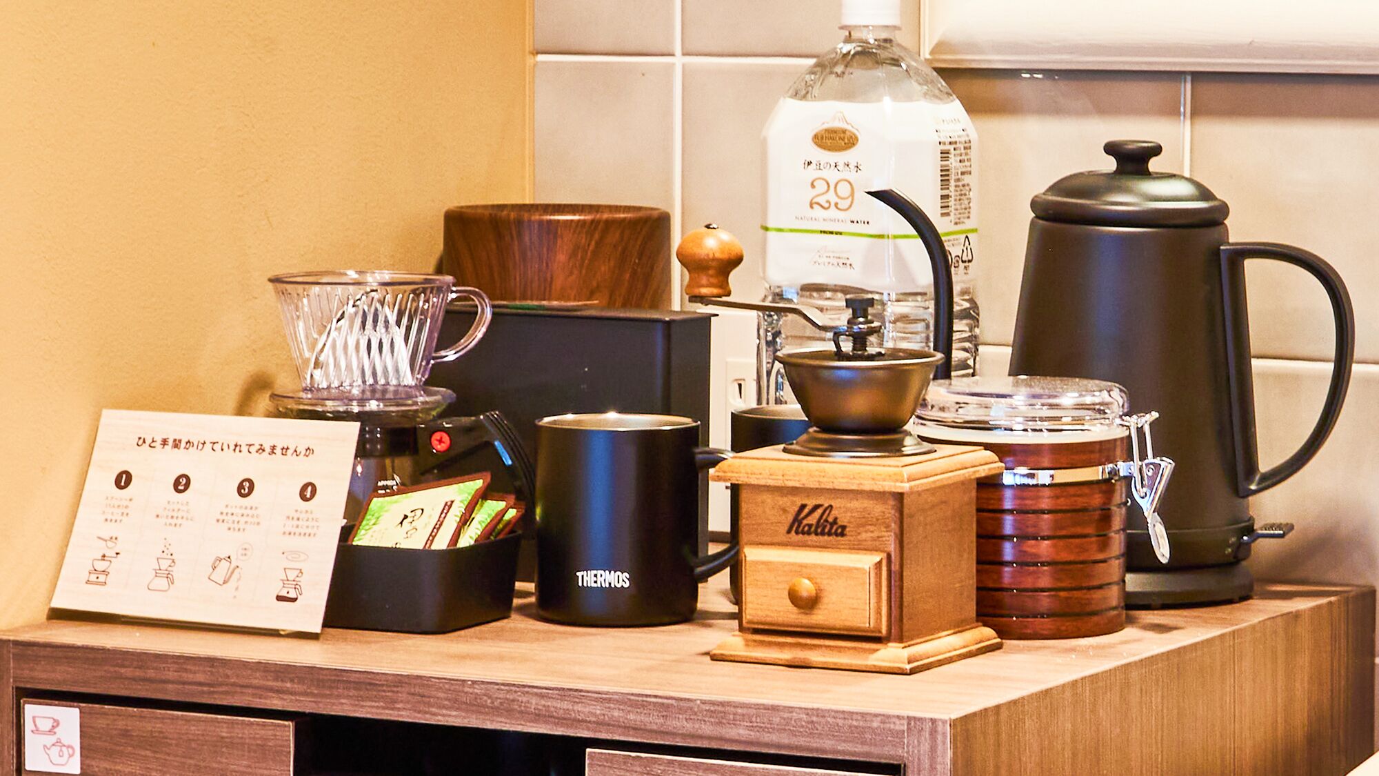 Eine Kaffeestation mit Kaffeemaschine, Thermoskanne, Wasserkocher und einer Wasserflasche.