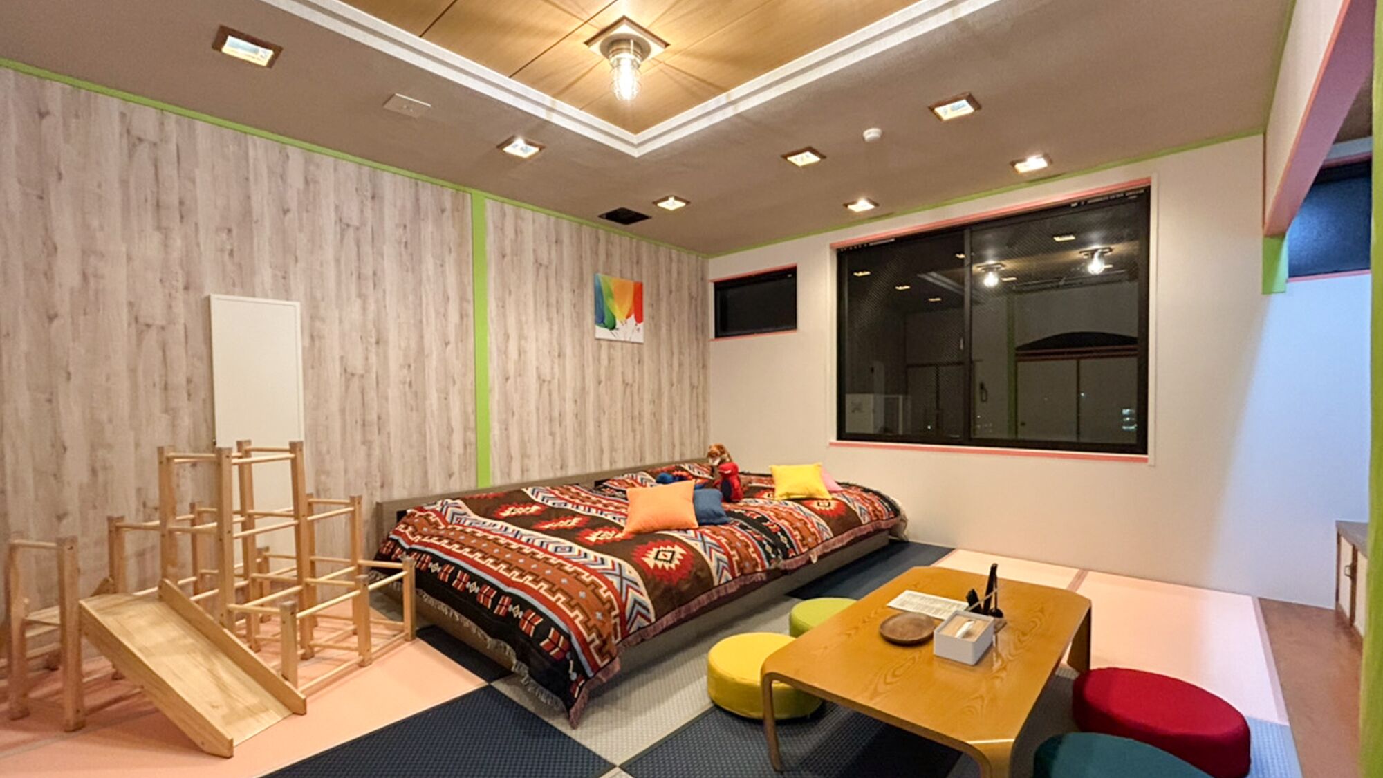 Ein Zimmer mit einem Bett, einem Schreibtisch, einem Stuhl, einem kleinen Tisch, einem Fenster und einer Holzleiter.