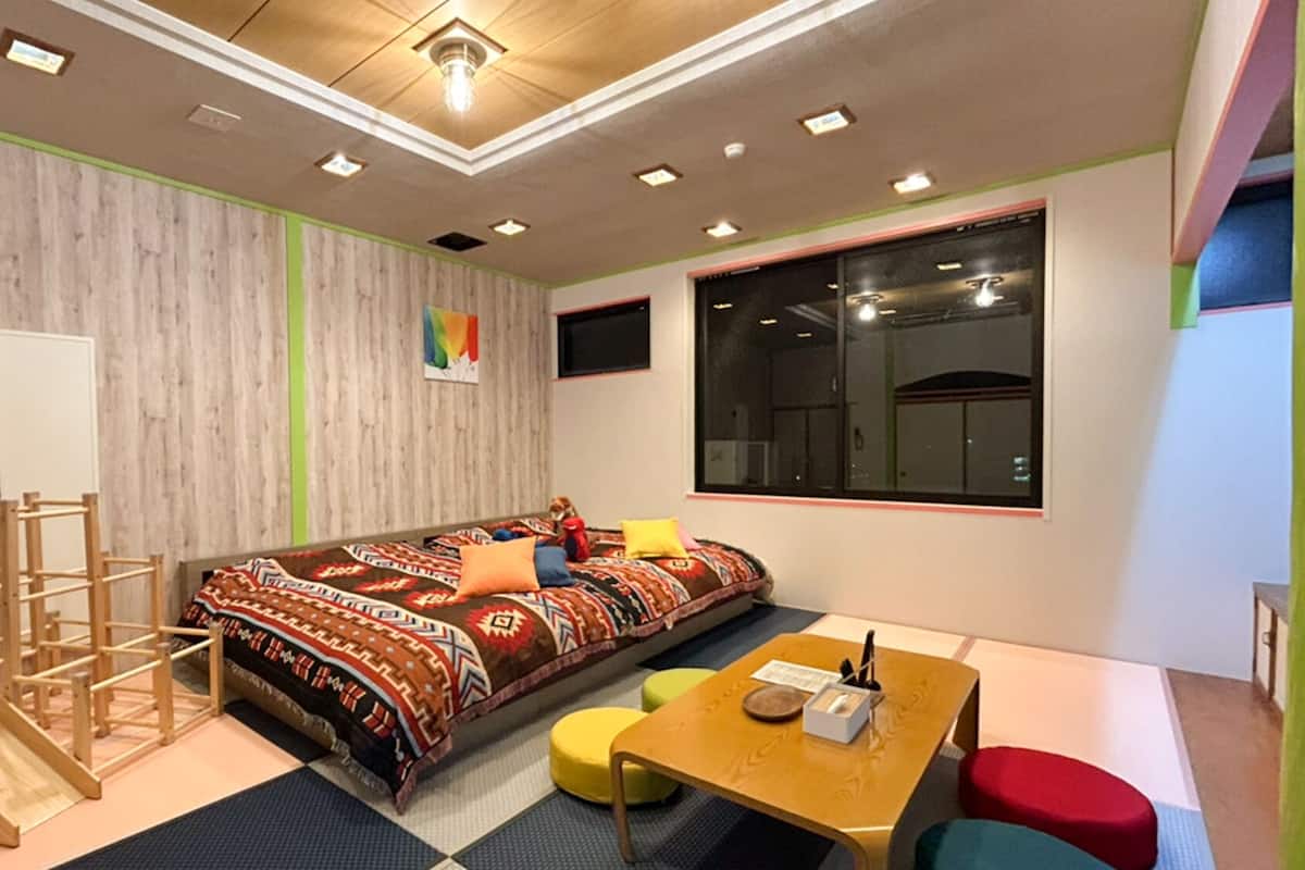 Ein Zimmer mit einem Bett, einem Schreibtisch, einem Stuhl, einem kleinen Tisch, einem Fenster und einer Holzleiter.