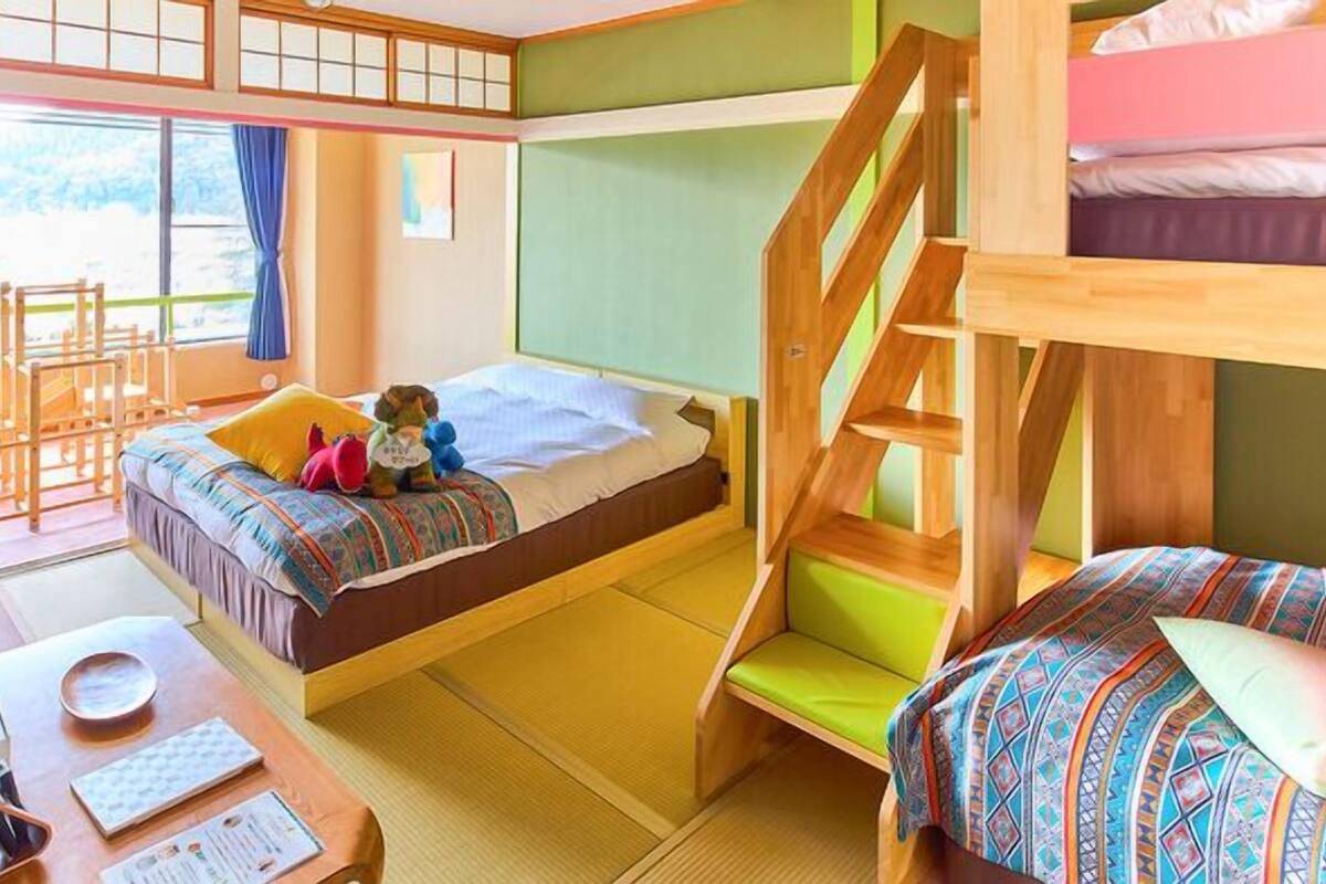 A bunk bed room with a desk, chair, and a window with curtains.
