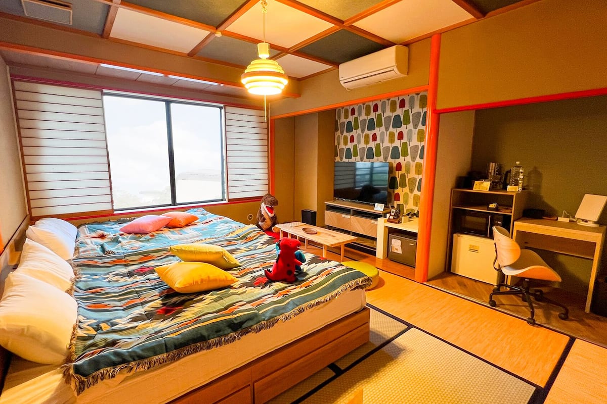 Ein Schlafzimmer mit Bett, Schreibtisch, Stuhl, Fernseher und Klimaanlage.