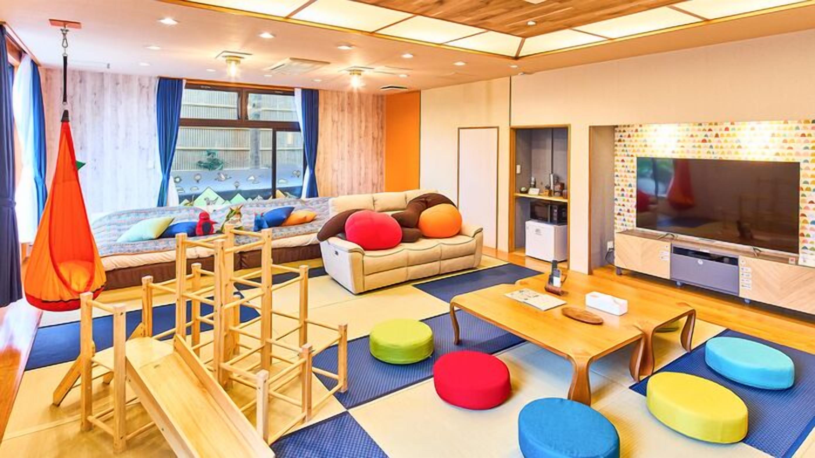 Ein modernes Wohnzimmer mit einer Couch, bunten Kissen, einem Fernseher und einer Holz-Spielstruktur.