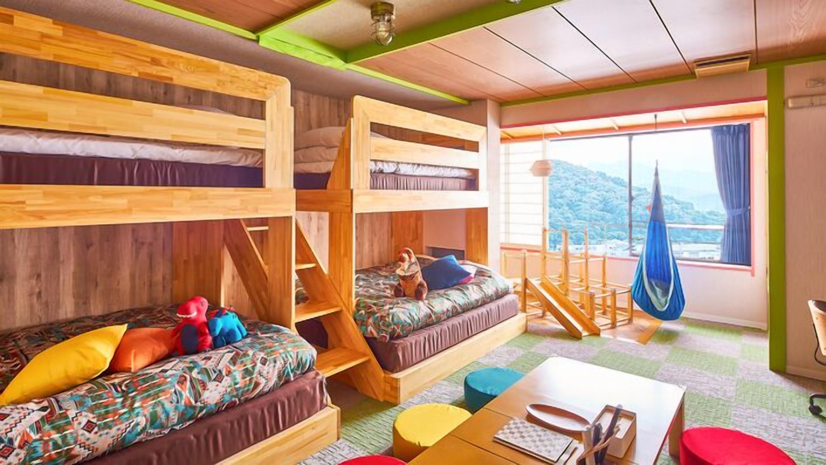 Ein Zimmer mit Etagenbetten, einer Schlafcouch, einer Hängematte und Blick ins Freie.
