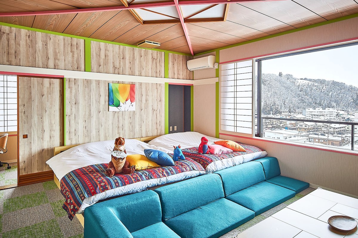 Ein Zimmer mit Bett, Sofa, Schreibtisch und einem Fenster mit Aussicht.