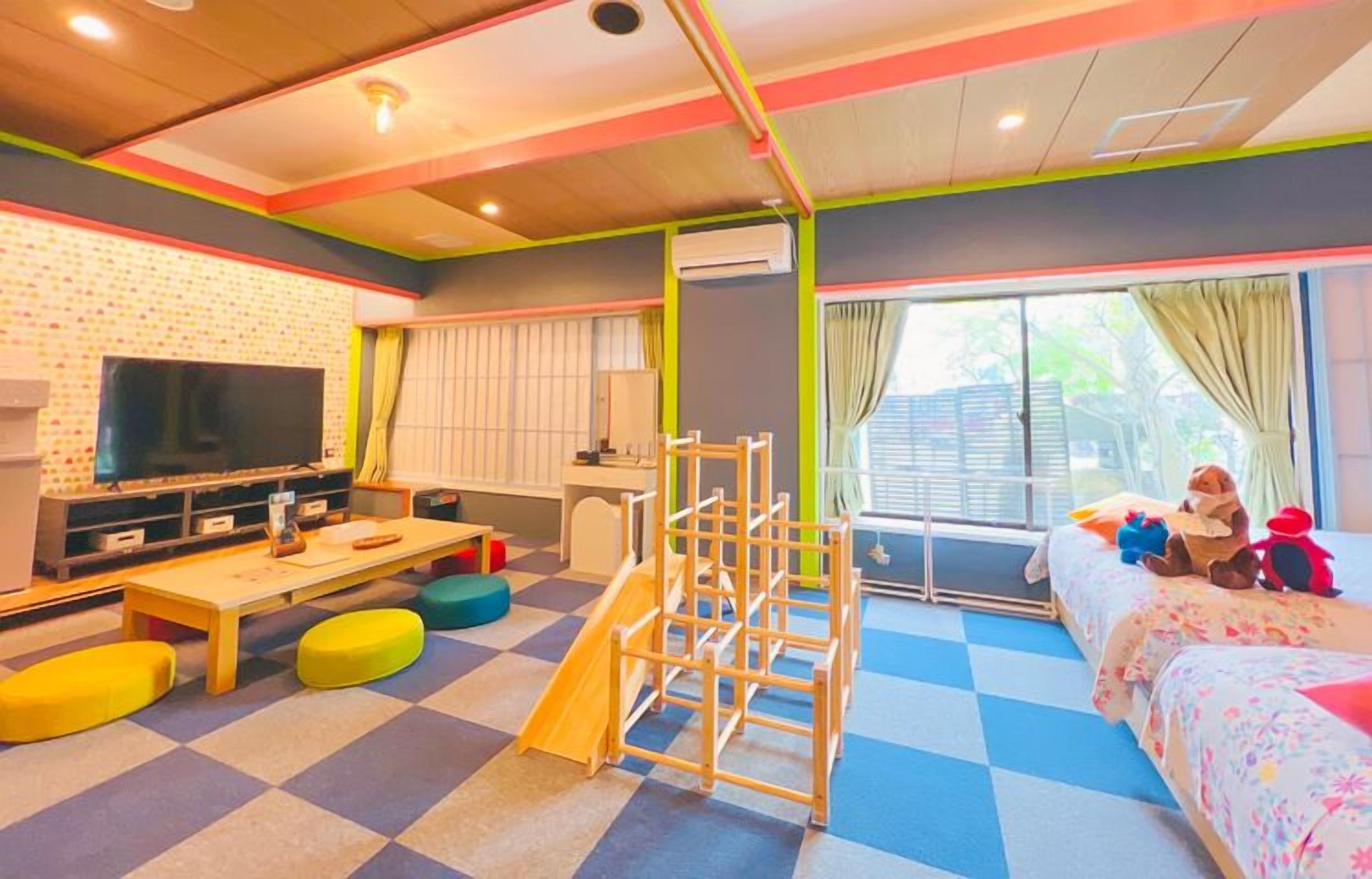 Ein Spielzimmer für Kinder mit Fernseher, Spielbereich und einem Bett voller Spielzeug.