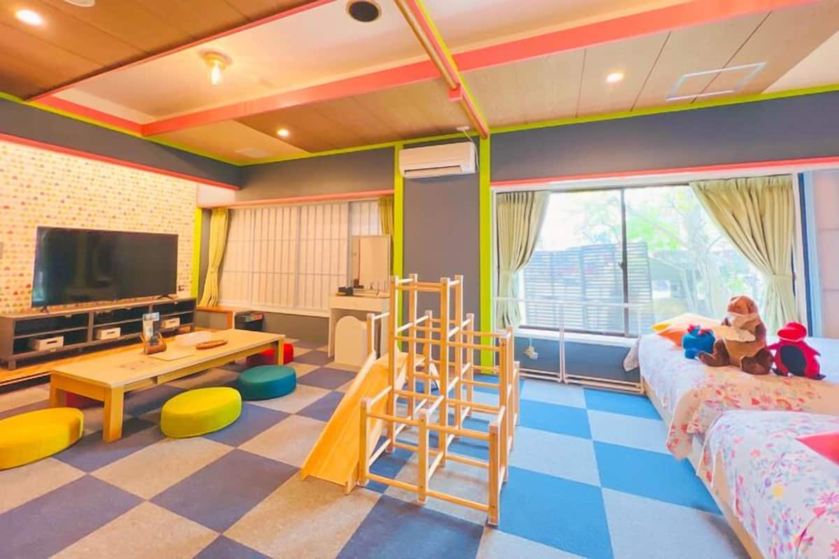 Ein Spielzimmer für Kinder mit Fernseher, Spielbereich und einem Bett voller Spielzeug.