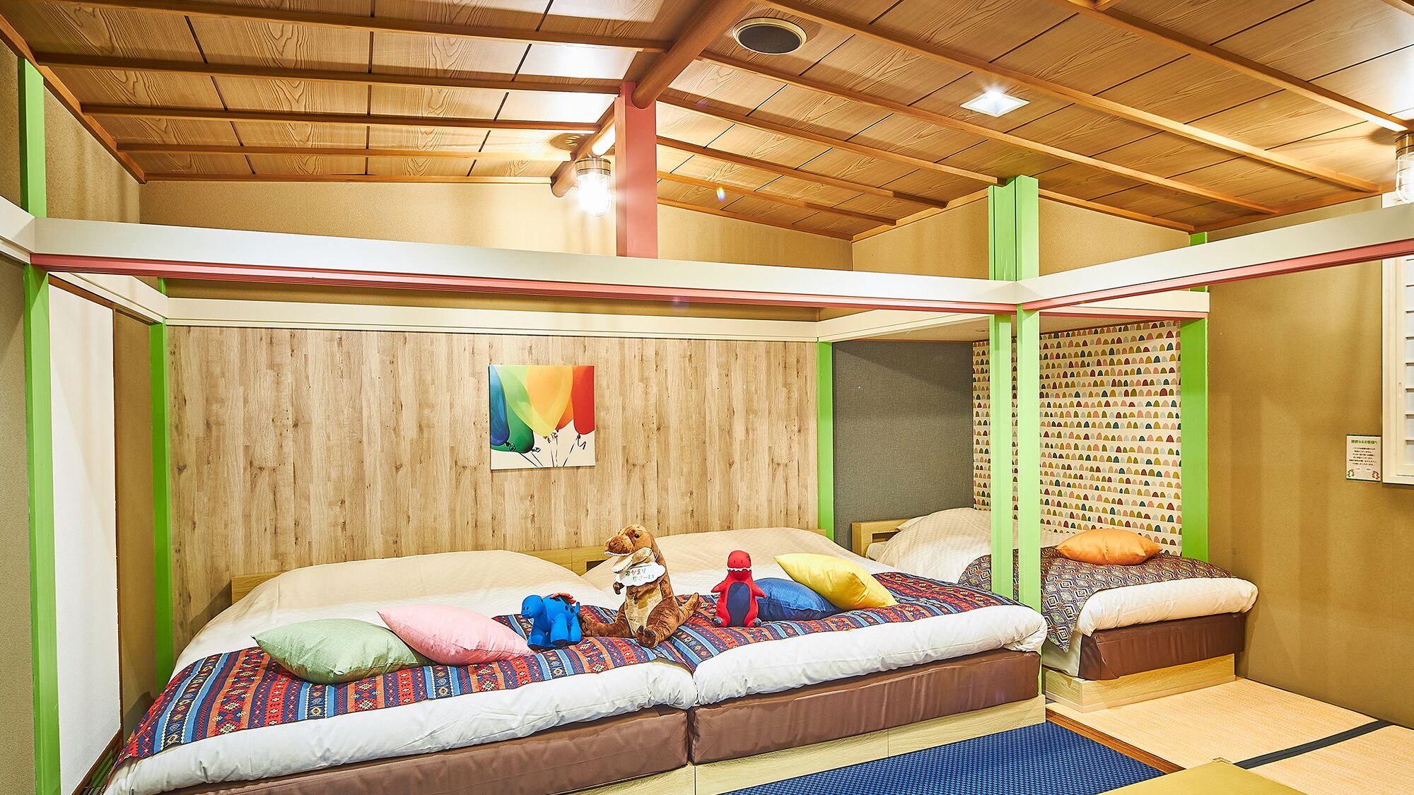 Ein Zimmer mit Holzboden, einem Bett mit bunter Bettwäsche und einer Wand mit einem gemusterten Design.