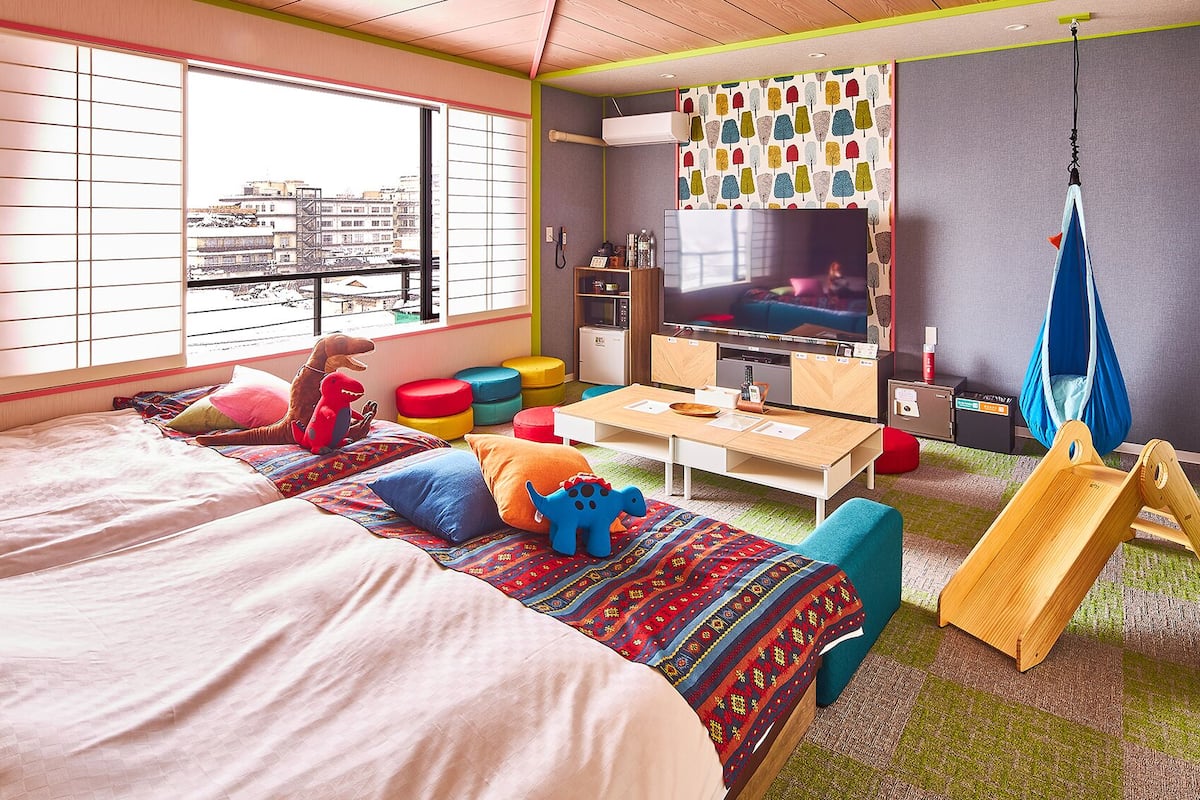 Ein modernes Hotelzimmer mit Bett, Fernseher, Schreibtisch und einem Schaukelstuhl.