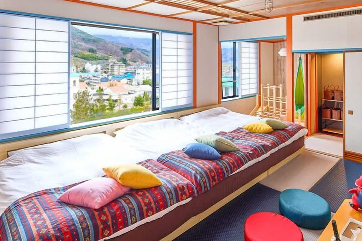 Ein Zimmer mit Bett, Blick auf eine Stadt, einem Kleiderschrank und einem kleinen Tisch mit einem Spielzeug.