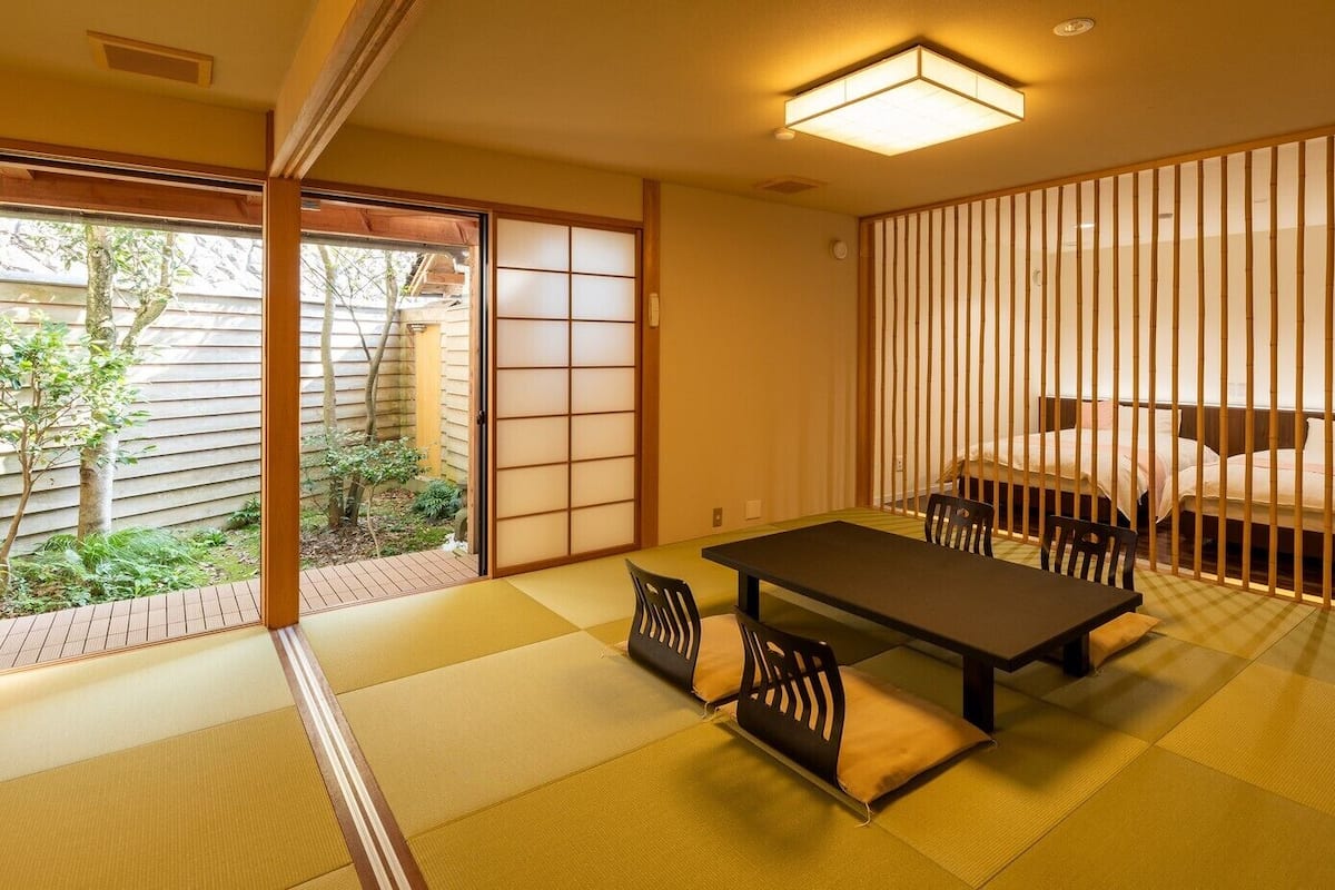 A traditional Japanese room with tatami flooring, a low table, and a bed with a shoji screen.