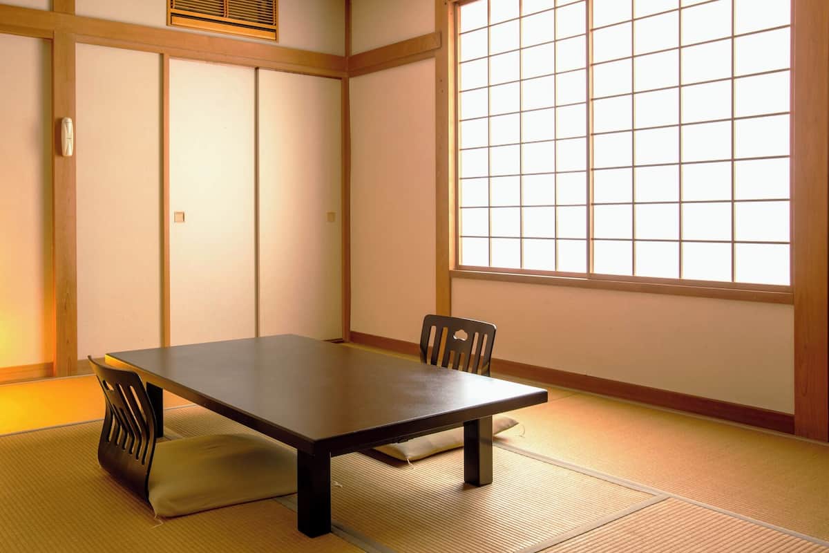 A traditional Japanese room with tatami flooring, a low table, and sliding doors.
