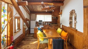 A wooden interior with a dining table, chairs, a kitchen area, and a skylight. - Kawazu Log House (Kawazu)