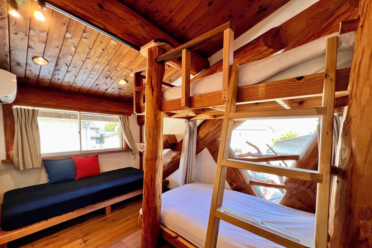 A cabin interior with a bunk bed, a sofa, and a window with curtains.