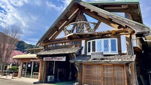 A traditional wooden building with a sloped roof, a small balcony, and a sign for a washbasin. - Kawazu Log House (Kawazu)