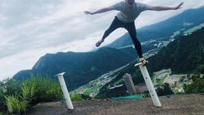 A person jumping between two poles with a mountainous landscape in the background. - Pension Tama House (Yuzawa)