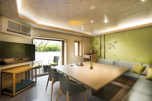 A modern living room with a large flat-screen TV, a wooden coffee table, a sofa, and a dining table with chairs. - Hakone Pet-friendly Inn Yuniwa (Hakone)