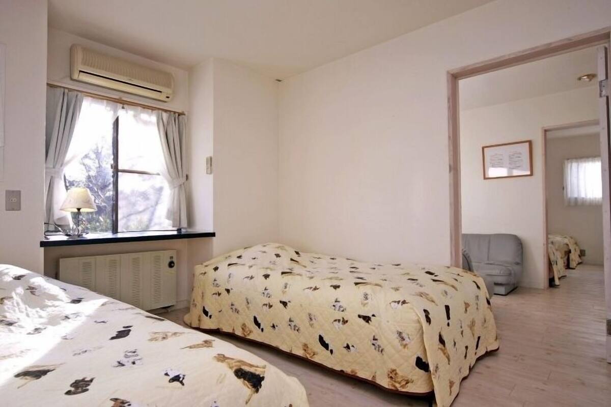 Une pièce avec un lit, une fenêtre avec des rideaux, un radiateur et une chaise.