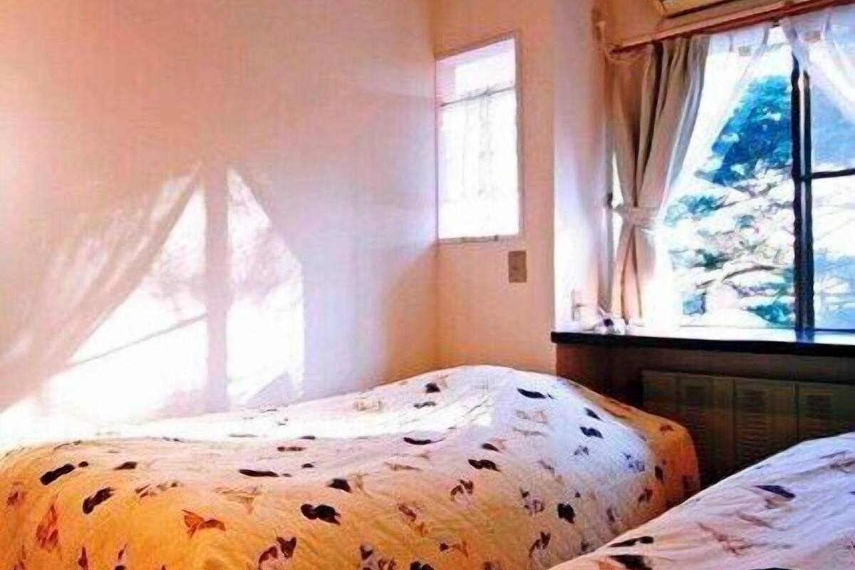 Une chambre avec deux lits, une fenêtre avec des rideaux et un climatiseur fixé au mur.
