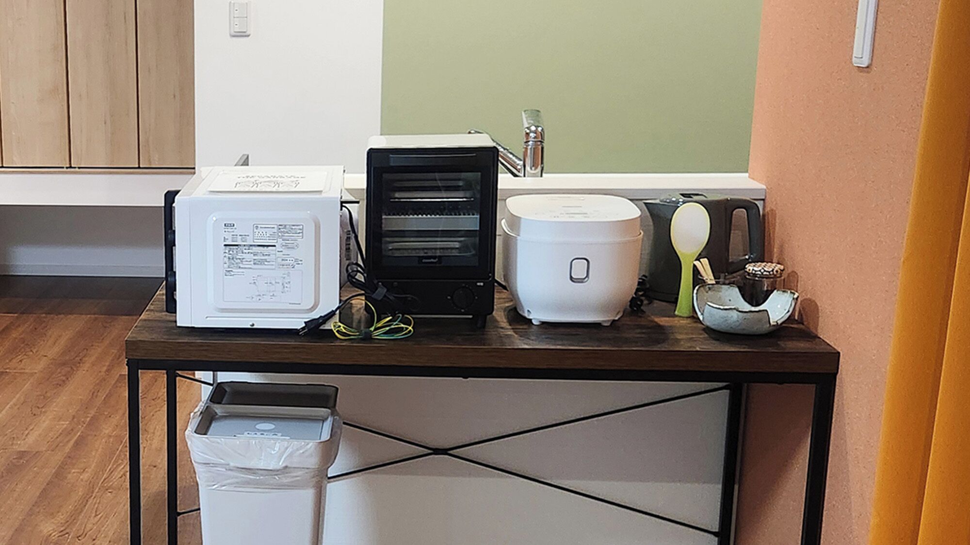 Un plan de travail de cuisine avec un four à micro-ondes, un grille-pain, un cuiseur à riz et un petit objet décoratif.