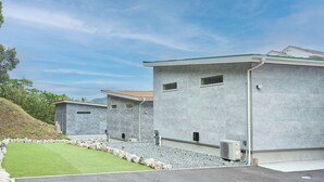 A row of modern buildings with a flat roof, a stone pathway, and a grassy area. - Chokotto Villa Maestro (Sumoto)