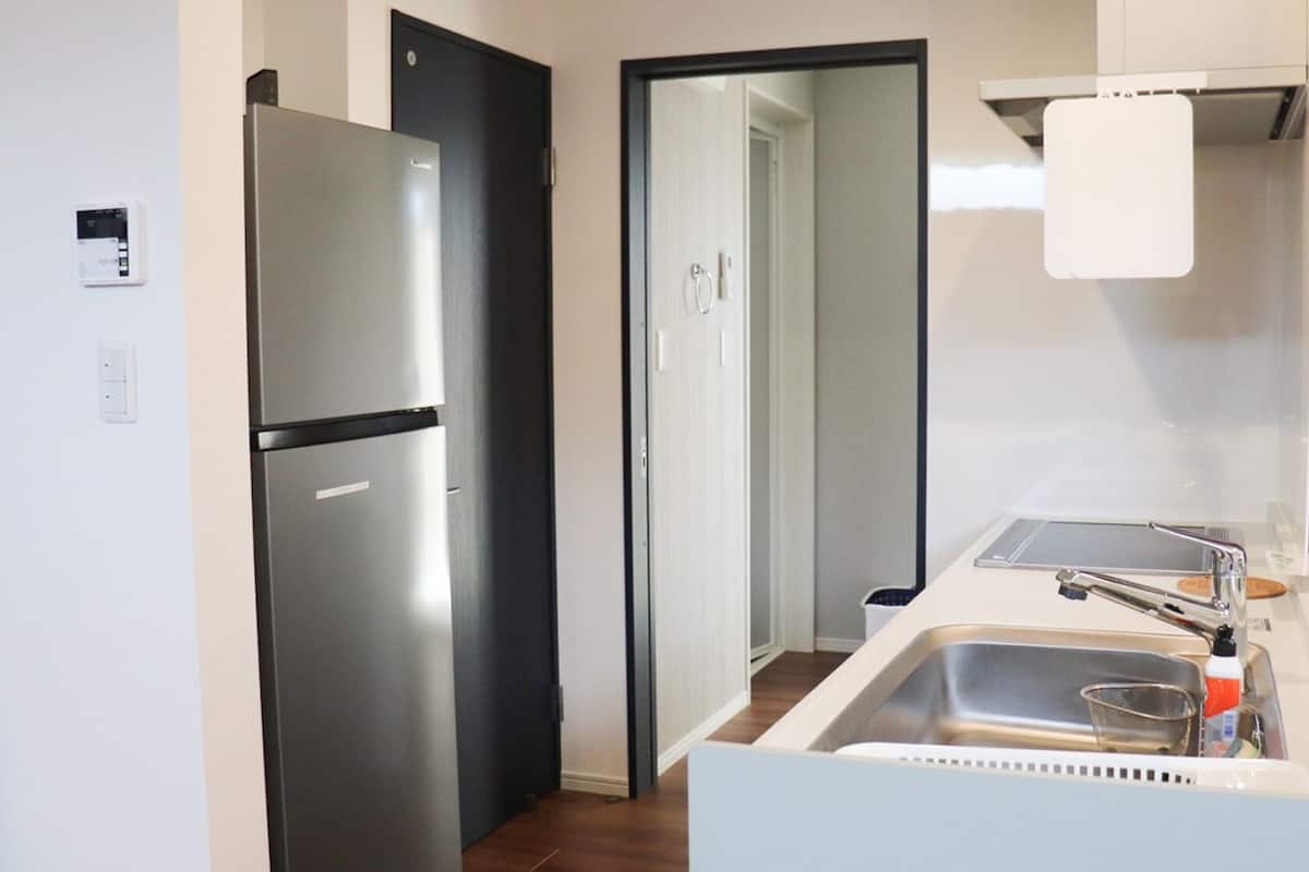 Eine moderne Küche mit einem Edelstahl-Kühlschrank, einer Spüle und einer weißen Arbeitsplatte.